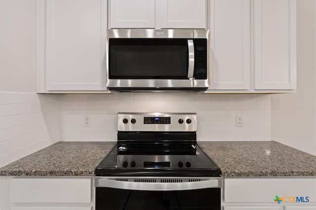 kitchen featuring white cabinetry, stainless steel appliances, tasteful backsplash, and dark stone countertops