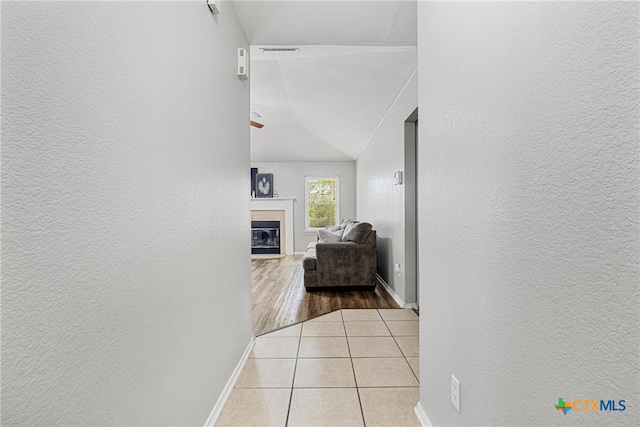 hall with lofted ceiling and light tile patterned flooring