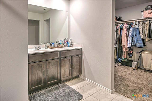 4001 Arafel Ln, Killeen, TX 76542 - bathroom featuring a sink, double vanity, a spacious closet, tile patterned flooring, and a textured wall