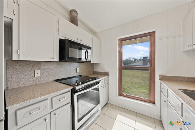 kitchen with decorative backsplash, light tile patterned floors, white cabinets, and electric stove