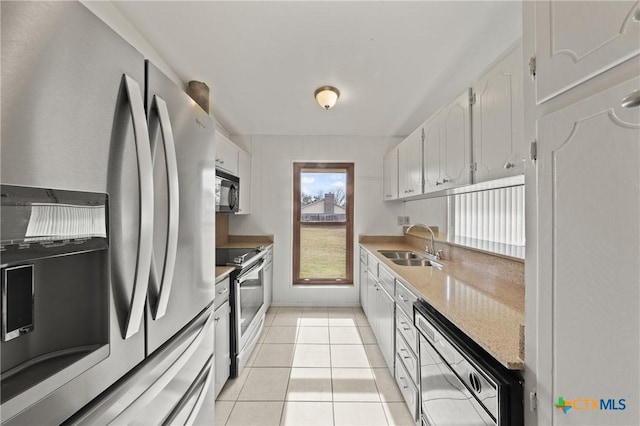 kitchen with appliances with stainless steel finishes, sink, light tile patterned floors, and white cabinets