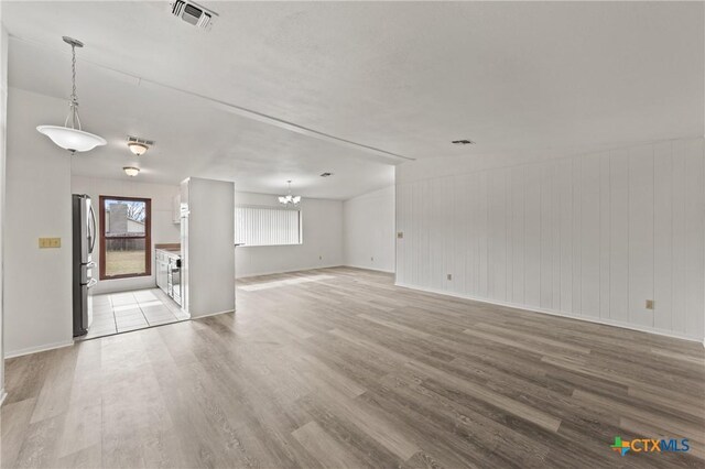 unfurnished living room featuring vaulted ceiling with beams, ceiling fan, and light wood-type flooring