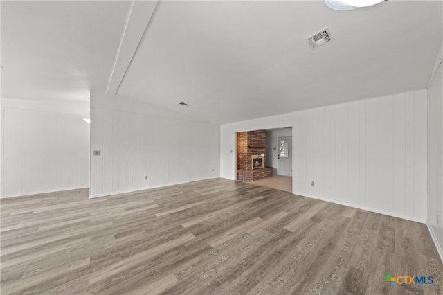 unfurnished living room with a brick fireplace and light hardwood / wood-style flooring