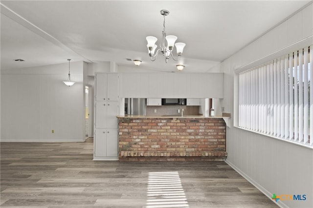 kitchen featuring white cabinetry, hanging light fixtures, stainless steel fridge, and hardwood / wood-style floors