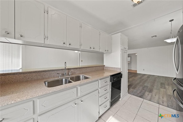 kitchen with stainless steel refrigerator, white cabinetry, black dishwasher, sink, and hanging light fixtures