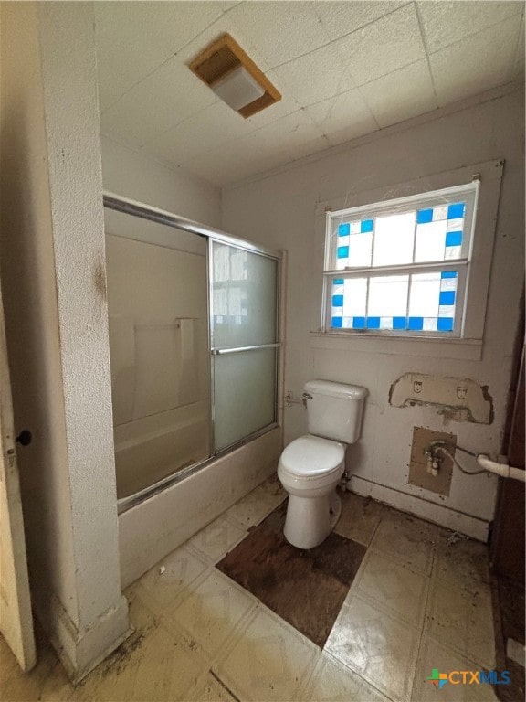 bathroom with shower / bath combination with glass door and toilet