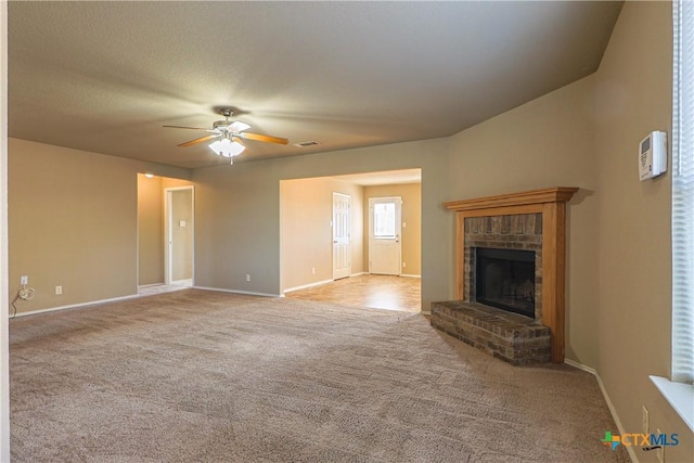 unfurnished living room featuring light carpet, a fireplace, ceiling fan, and a textured ceiling