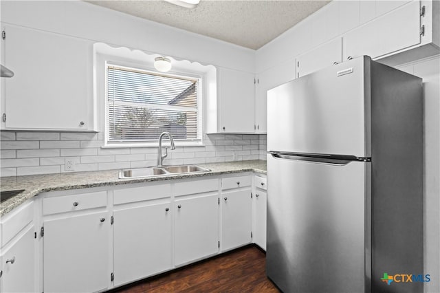 kitchen featuring white cabinetry, sink, backsplash, dark wood-type flooring, and stainless steel fridge