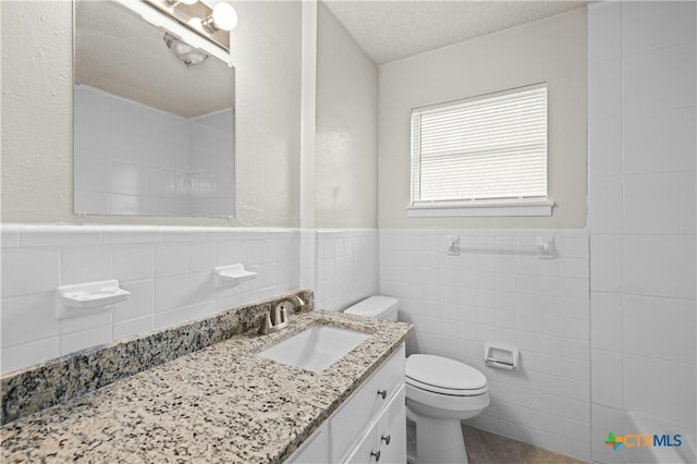 bathroom with tile walls, vanity, a textured ceiling, hardwood / wood-style flooring, and toilet