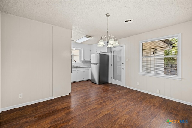 kitchen with white cabinetry, a healthy amount of sunlight, dark hardwood / wood-style floors, and stainless steel refrigerator