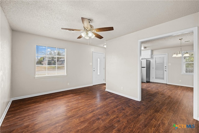 unfurnished room featuring a textured ceiling, dark hardwood / wood-style floors, and ceiling fan with notable chandelier