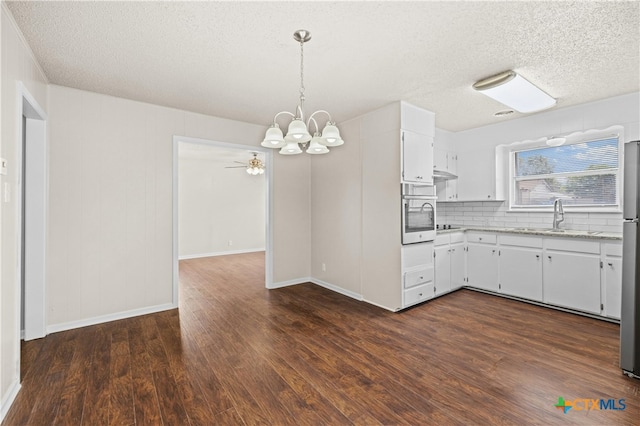 kitchen featuring decorative light fixtures, dark hardwood / wood-style flooring, sink, decorative backsplash, and white cabinets