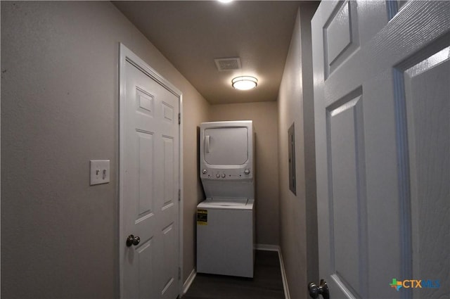 washroom featuring laundry area, dark wood-style flooring, visible vents, stacked washer / drying machine, and baseboards