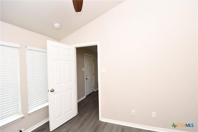 spare room featuring baseboards, ceiling fan, vaulted ceiling, and dark wood finished floors