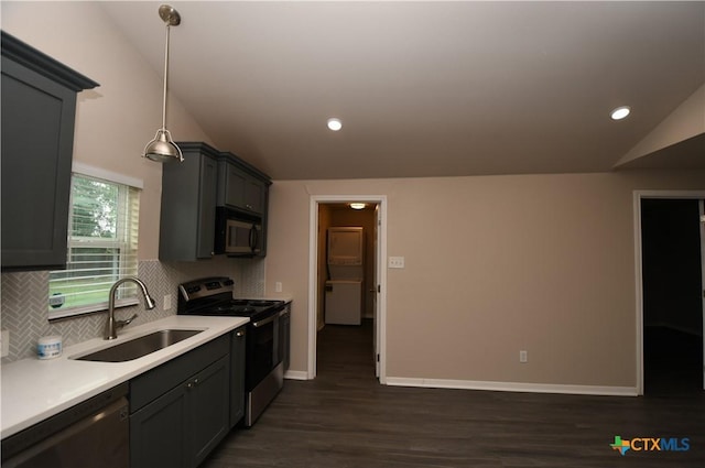 kitchen featuring appliances with stainless steel finishes, a sink, decorative backsplash, lofted ceiling, and dark wood-type flooring