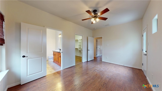 1802 Spring Valley Dr, Dripping Springs, TX 78620 - unfurnished bedroom featuring light wood finished floors, a walk in closet, a closet, connected bathroom, and ceiling fan