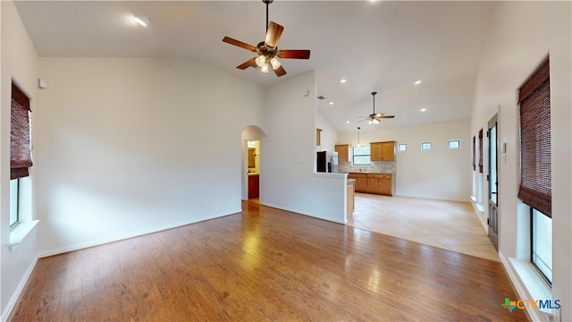1802 Spring Valley Dr, Dripping Springs, TX 78620 - unfurnished living room with a ceiling fan, arched walkways, light wood finished floors, and high vaulted ceiling