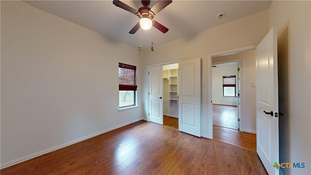 1802 Spring Valley Dr, Dripping Springs, TX 78620 - unfurnished bedroom featuring multiple windows, dark wood finished floors, a closet, and a ceiling fan