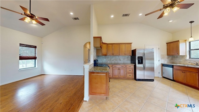 1802 Spring Valley Dr, Dripping Springs, TX 78620 - kitchen featuring stainless steel appliances, ceiling fan, brown cabinets, decorative backsplash, and high vaulted ceiling