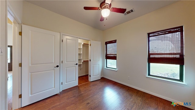 1802 Spring Valley Dr, Dripping Springs, TX 78620 - unfurnished bedroom with wood finished floors, a closet, a walk in closet, and a ceiling fan