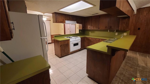 kitchen with white appliances, sink, light tile patterned floors, a textured ceiling, and kitchen peninsula