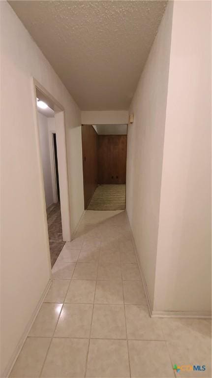 hallway featuring light tile patterned flooring and a textured ceiling