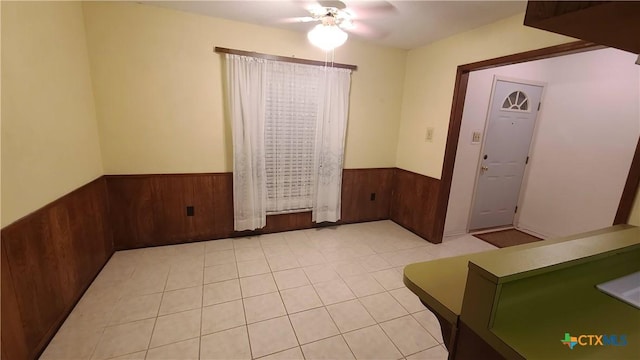 tiled foyer entrance with ceiling fan and wooden walls