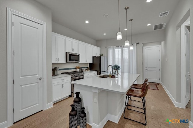 kitchen with a sink, stainless steel appliances, light wood-style flooring, and visible vents