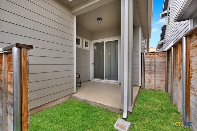 view of exterior entry featuring fence and a patio