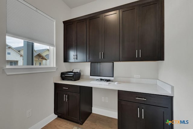 unfurnished office with baseboards and light wood-style flooring