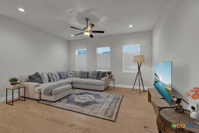 living area with visible vents, a ceiling fan, light wood-style floors, and baseboards
