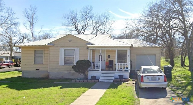 bungalow-style house featuring covered porch, a garage, and a front lawn