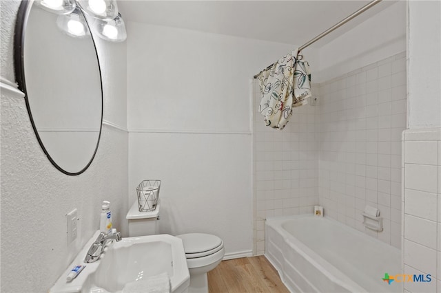 full bathroom featuring sink, wood-type flooring, tiled shower / bath combo, and toilet