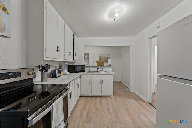 kitchen featuring white cabinetry, sink, white fridge, stainless steel range with electric stovetop, and light wood-type flooring