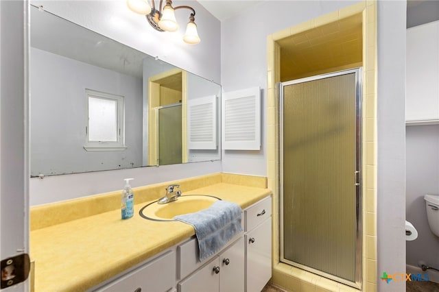 bathroom with toilet, a stall shower, and vanity