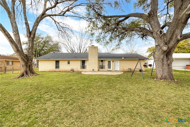 back of property with a lawn, a chimney, fence, a patio area, and brick siding