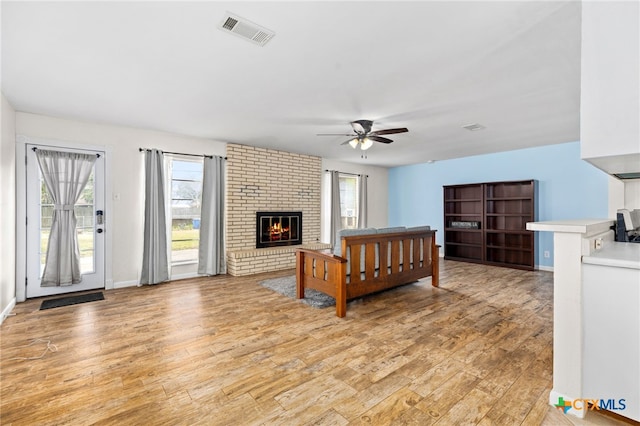 bedroom with visible vents, a fireplace, light wood-style flooring, and multiple windows