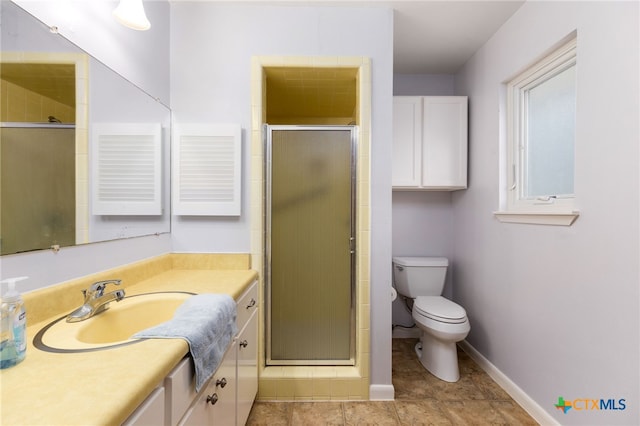 bathroom with toilet, a shower stall, baseboards, and vanity