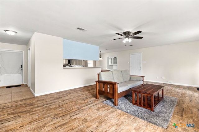 living room with baseboards, wood-type flooring, visible vents, and a ceiling fan