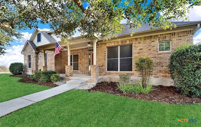 view of front of home with a front yard, brick siding, and roof with shingles