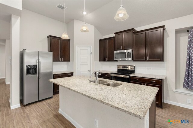 kitchen with pendant lighting, sink, appliances with stainless steel finishes, and an island with sink