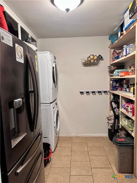 3043 Boys Ranch Rd, Kempner, TX 76539 - laundry room with estacked washer and dryer, a textured ceiling, and light tile patterned floors