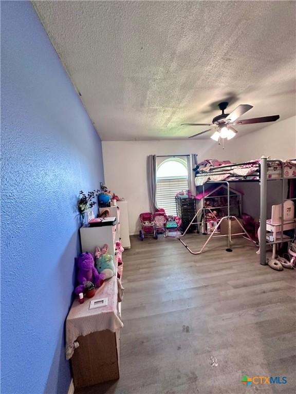 3043 Boys Ranch Rd, Kempner, TX 76539 - bedroom with a textured ceiling, a textured wall, ceiling fan, and wood finished floors