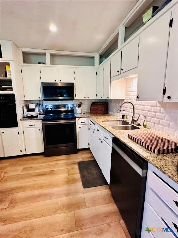 3043 Boys Ranch Rd, Kempner, TX 76539 - kitchen with black appliances, white cabinets, decorative backsplash, and light wood finished floors