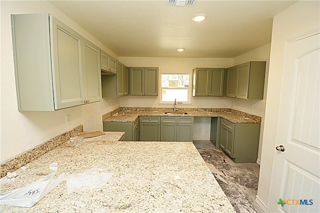 kitchen with light stone countertops, sink, and a textured ceiling