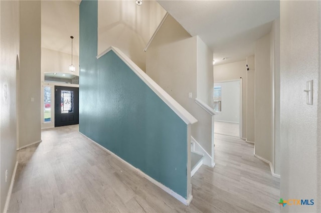 hallway with baseboards, a high ceiling, stairway, and wood finished floors