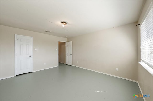 unfurnished room featuring visible vents, finished concrete flooring, and baseboards