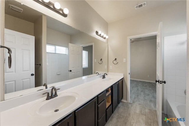 bathroom with double vanity, a sink, visible vents, and baseboards