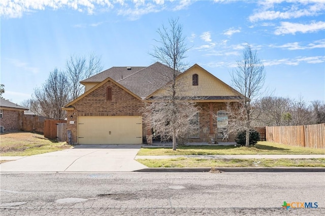 view of front of home featuring driveway, brick siding, roof with shingles, fence, and a front yard