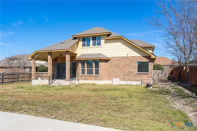 view of front of home featuring roof with shingles, brick siding, a front lawn, and a fenced backyard